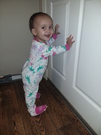 Portrait of cute girl standing on hardwood floor at home