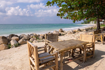 Chairs and table at beach against sky