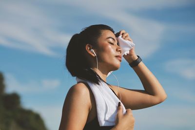 Young woman drinking water against sky