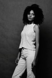 Portrait of young woman standing against gray background