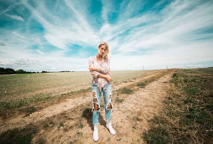 cloud - sky, full length, sky, one person, landscape, casual clothing, road, nature, front view, transportation, grass, portrait, dirt, day, dirt road, land, environment, young adult, outdoors, hairstyle