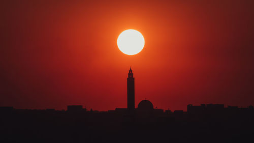 Silhouette lighthouse against orange sky