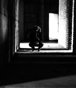 Full length of man crouching in abandoned building