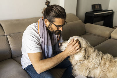 Satisfied guy petting retriever at home