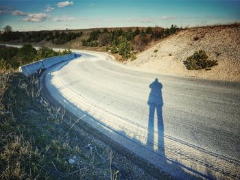 Shadow of person on street against sky