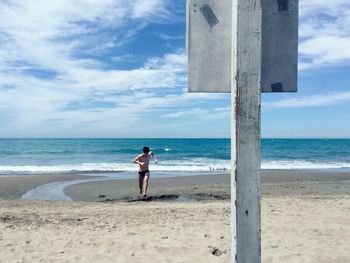 Full length of woman standing on beach against sky