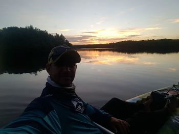 Portrait of man in lake against sky during sunset