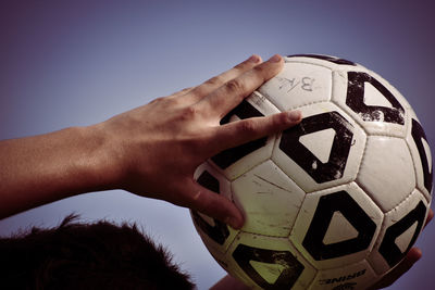 Low section of man playing soccer ball against sky