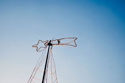 Low angle view of metal star against clear blue sky