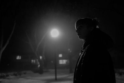 Side view of woman standing on street at night