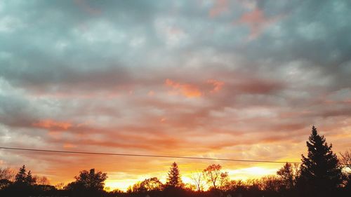 Low angle view of silhouette trees against dramatic sky