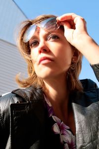 Woman holding sunglasses while looking away