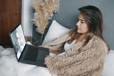 Young woman talking to doctor on video call at home