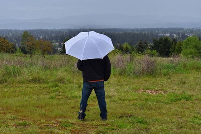 Man standing in spring rain looking out across landscape