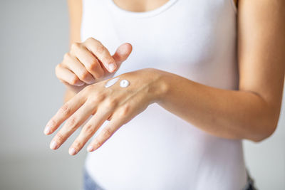 Close-up of woman holding hands over white background