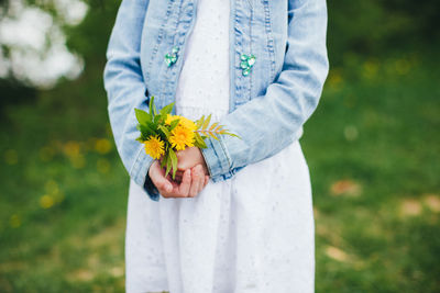 Low section of man standing by white flower on field