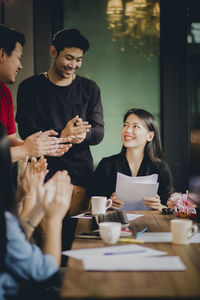 Colleagues applauding for businesswoman in meeting