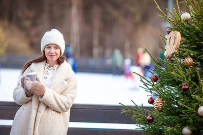 Portrait of young woman standing by tree