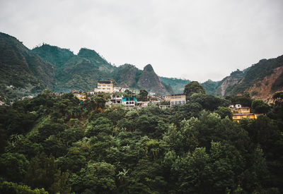 Houses by trees and mountains against sky