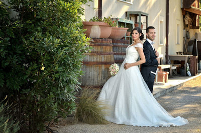 Side view portrait of wedding couple kissing while standing by trees