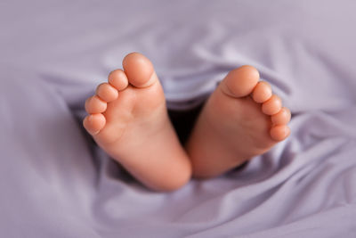 Low section of baby lying on bed