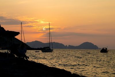 Sailboats in sea against sky during sunset