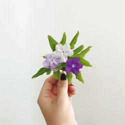 Close-up of hand holding flowers against white background