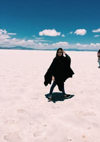 Full length of woman standing on beach against sky