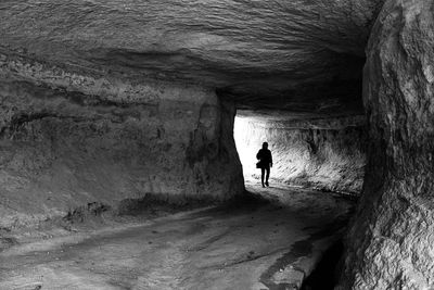 Rear view of silhouette man walking in cave