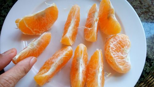 Close-up of hand holding fruit in plate