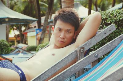 Portrait of man shirtless sitting on deckchair