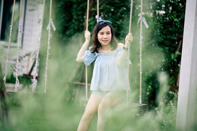 Young woman standing against plants