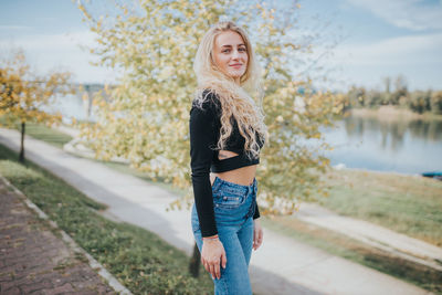 Portrait of beautiful young woman standing near water