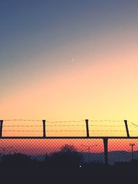 Silhouette fence against clear sky during sunset