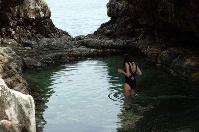 Rear view of woman standing against sea in pond