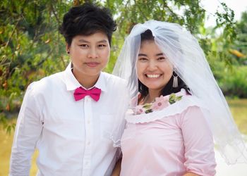 Portrait of lesbian couple standing against trees