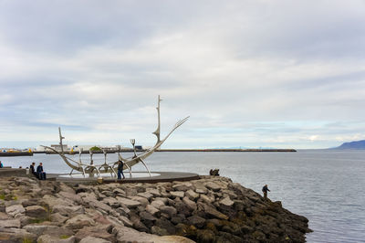 Scenic view of groyne by sea against sky