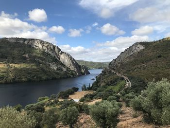 Scenic view of river by mountains against sky