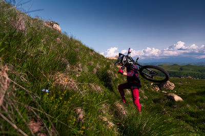 Male athlete cyclist carries his mountain bike uphill. summer downhill mtb bike concept