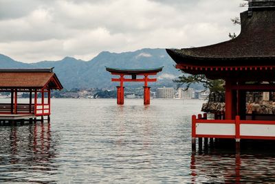 Torii gate in sea at itsukushima shrine against sky