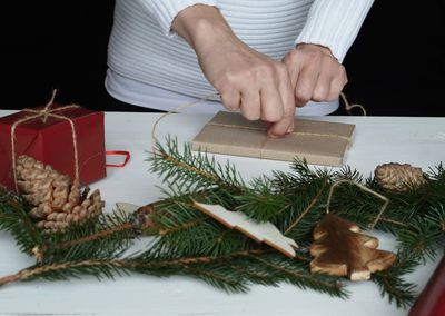 Midsection of man holding christmas tree on table