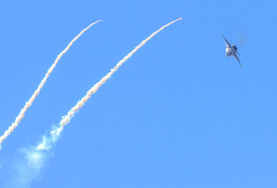 Low angle view of airplane flying against clear blue sky