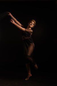 Woman looking away while standing against black background