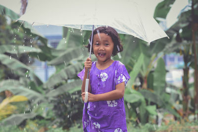 Portrait of a smiling girl standing on rainy day