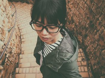 High angle view of woman standing on steps amidst stone wall