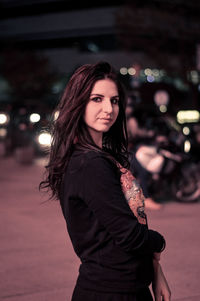 Side view portrait of young woman standing in city at night