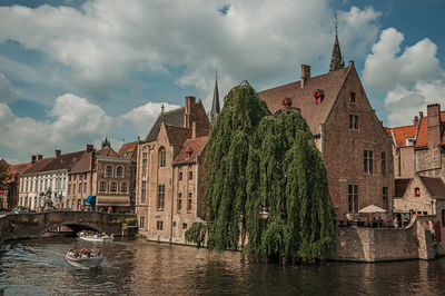 Panoramic view of buildings by river against cloudy sky