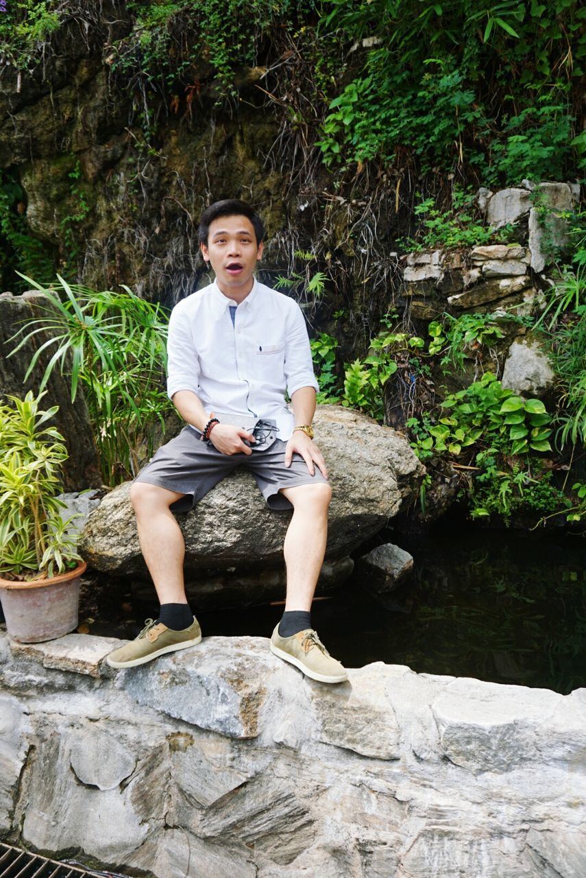 person, lifestyles, leisure activity, casual clothing, full length, portrait, rock - object, looking at camera, young adult, tree, smiling, sitting, water, three quarter length, standing, nature, front view, young women