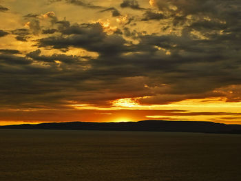 Scenic view of dramatic sky over land during sunset