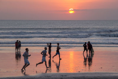 People on beach against sky during sunset